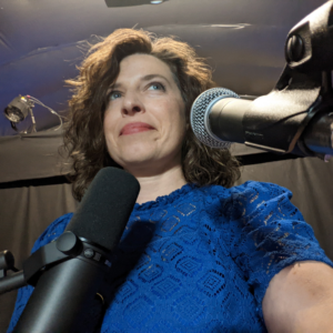 Clara smiles behind two mics